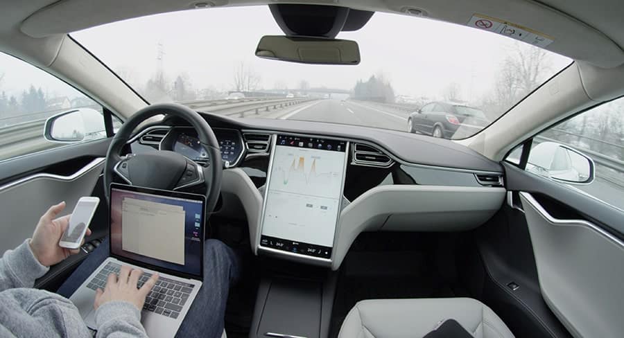 Man working on laptop while in self-driving car