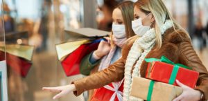 Women in masks holding gifts while Christmas shopping