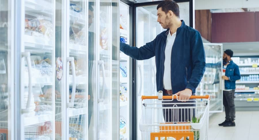 Man reaching into freezer while grocery shopping