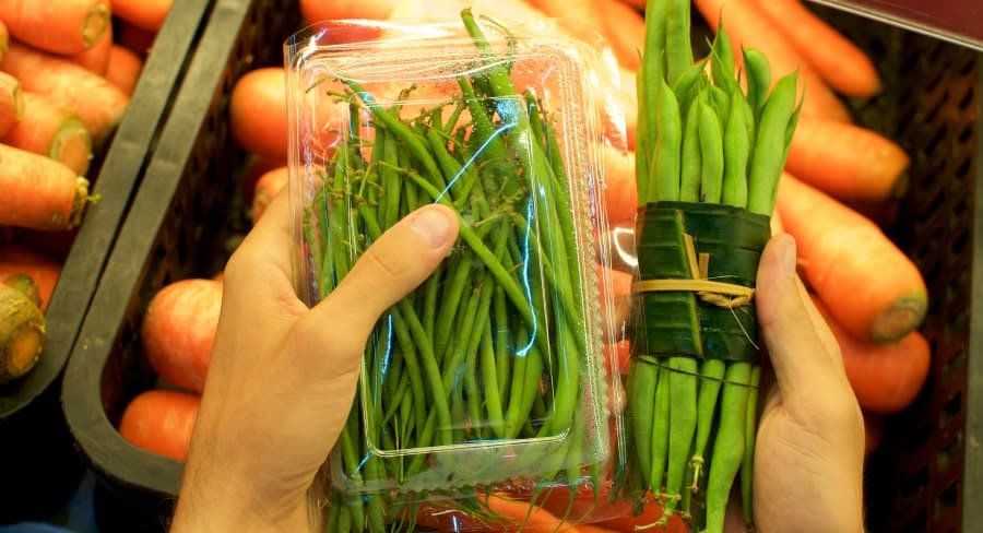 Person holding beans in plastic package and sustainable package